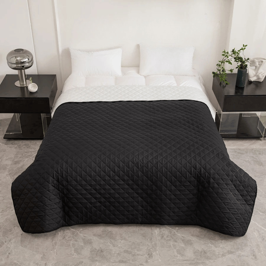 Black quilted cover on a bed in a modern bedroom setting