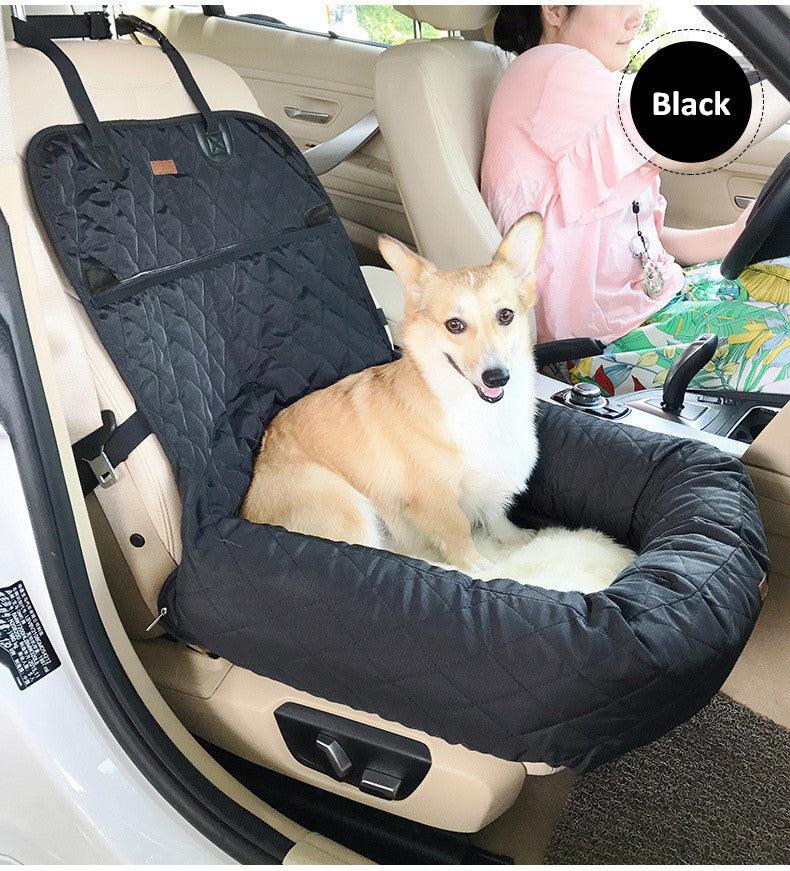 Corgi sitting in a dog car seat bed in black next to a woman driving