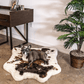 Dog lying on a cowhide rug in a room with a desk and plant.