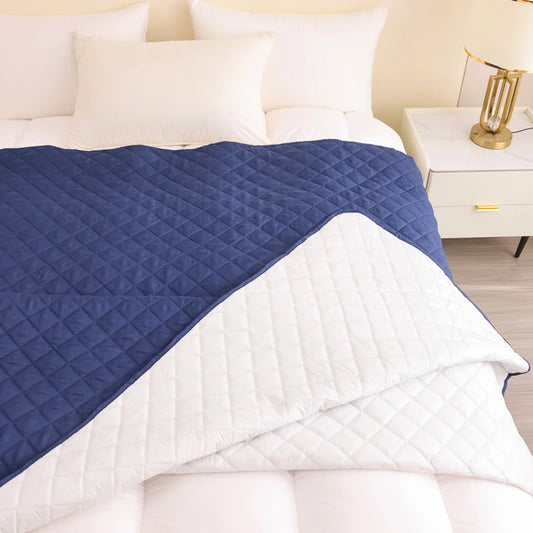 Blue and white quilted cover on a bed with a nightstand in the background