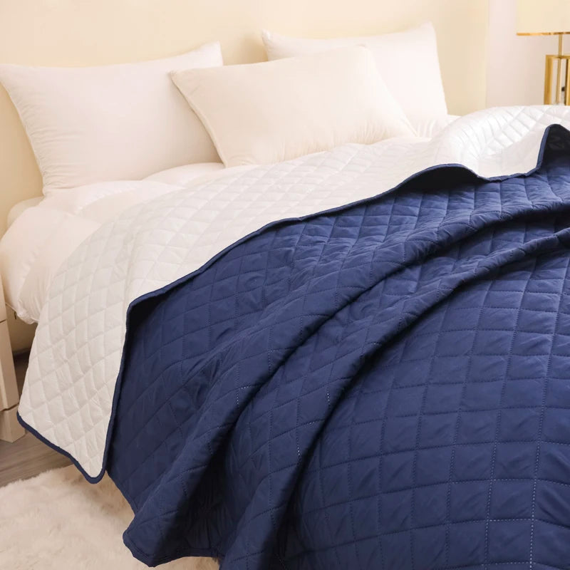 Navy quilt draped over a bed with white pillows in a bedroom setting