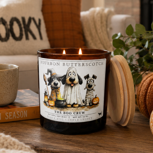 Candle labeled 'The Boo Crew' with Halloween-themed design on a wooden surface.