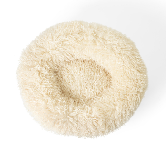 Round, fluffy white pet bed on a white background