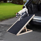 Small dog getting off the trunk of car using a wooden dog ramp
